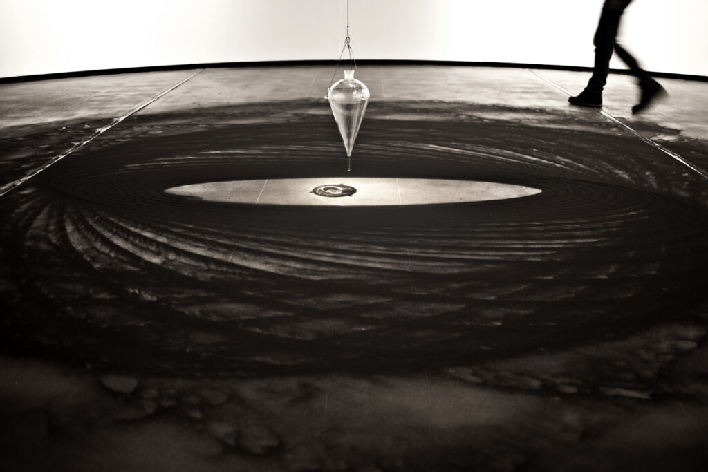 Instalação Movimento Pendular de Felippe Moraes com pêndulo desenhando curvas na areia.