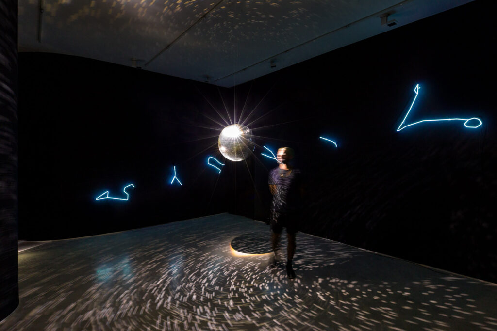Solaris Discotecum (2023), instalação de Felippe Moraes com constelações do zodíaco em néon e globo espelhado representando o sistema solar