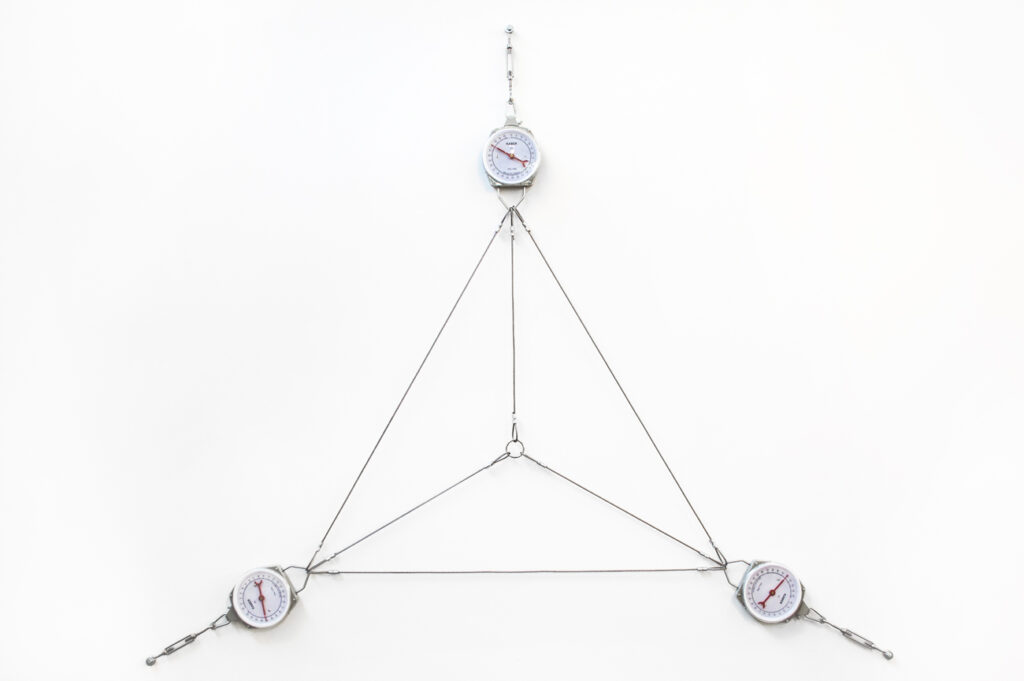Instalação 64kg de Triângulo (2014) de Felippe Moraes formada por cabos de aço tensionados e balanças que medem a força da estrutura triangular