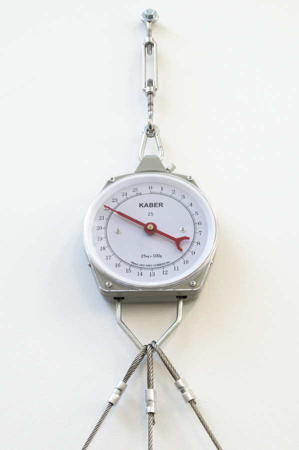 Instalação 64kg de Triângulo (2014) de Felippe Moraes formada por cabos de aço tensionados e balanças que medem a força da estrutura triangular