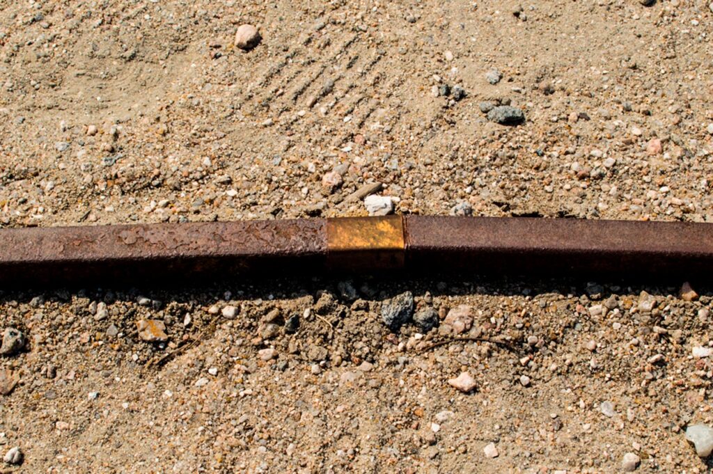 Detalhe do ponto dourado em latão na escultura Escala Humana.