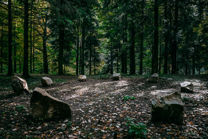 Vista ampla da instalação Monumento a Euclides composta por oito blocos de gresia de Kliwa dispostos em círculo em paisagem aberta na Romênia.