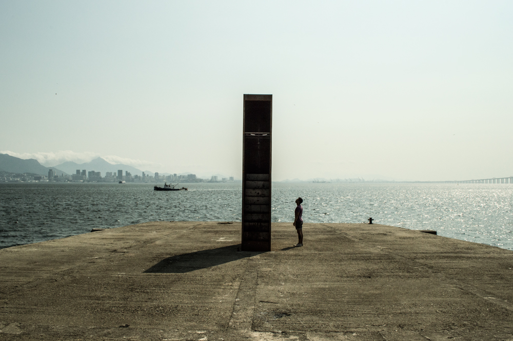 Registro da escultura Monumento ao Horizonte, instalada no Caminho Niemeyer em Niterói. A estrutura de aço corten funciona como um observatório que enquadra o horizonte da Baía de Guanabara, convidando o público a subir sua escada interna e contemplar a paisagem através de uma abertura voltada para o oeste.