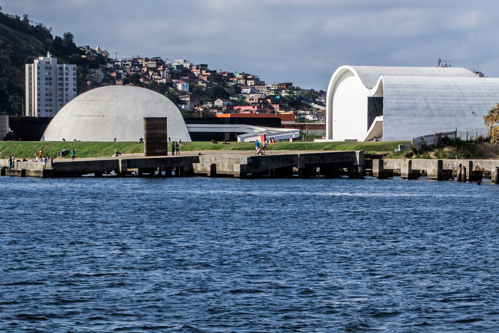 Registro da escultura Monumento ao Horizonte, instalada no Caminho Niemeyer em Niterói. A estrutura de aço corten funciona como um observatório que enquadra o horizonte da Baía de Guanabara, convidando o público a subir sua escada interna e contemplar a paisagem através de uma abertura voltada para o oeste.