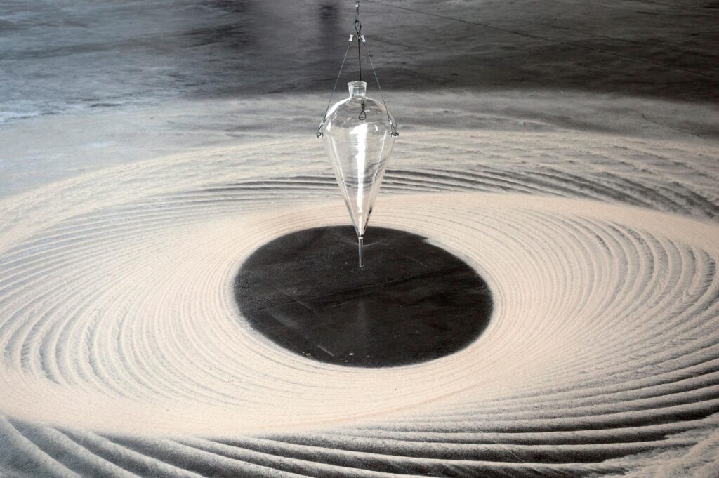 Instalação Movimento Pendular de Felippe Moraes com pêndulo desenhando curvas na areia.