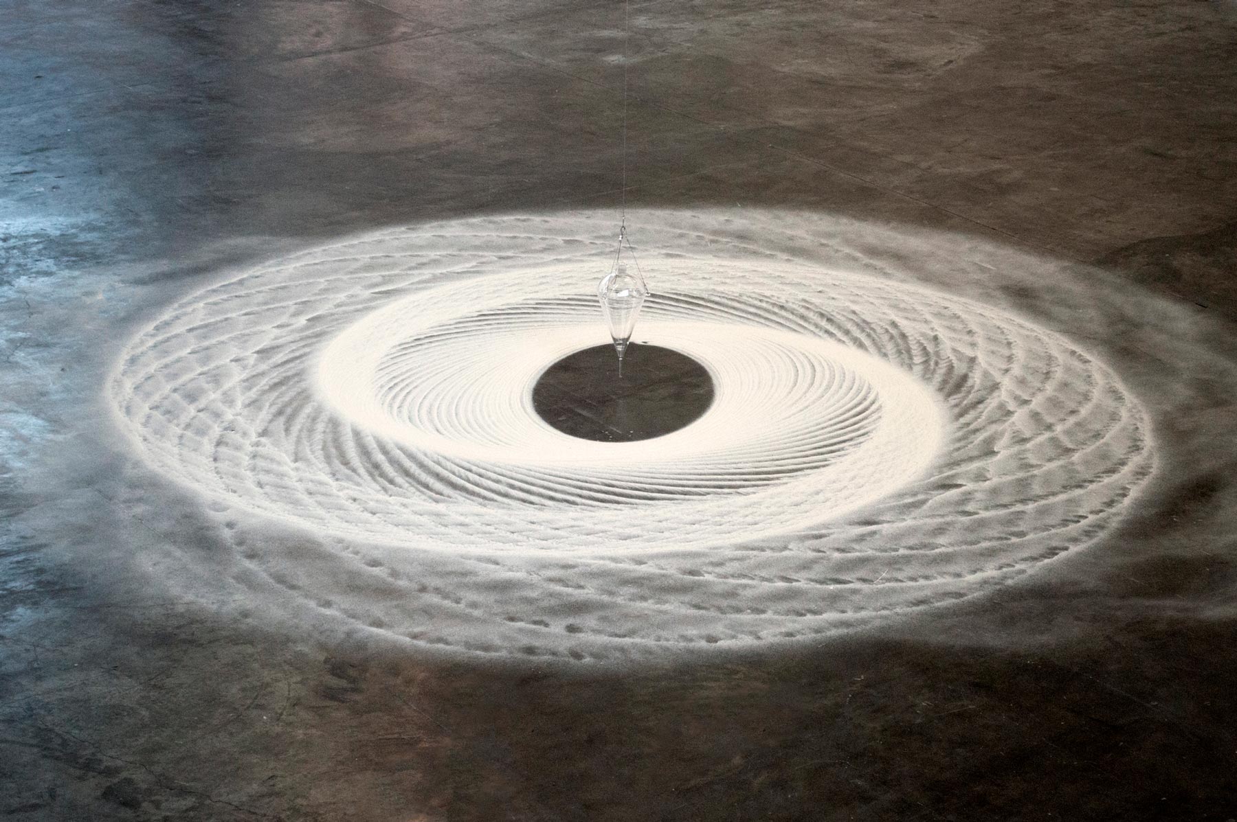 Instalação Movimento Pendular de Felippe Moraes com pêndulo desenhando curvas na areia.