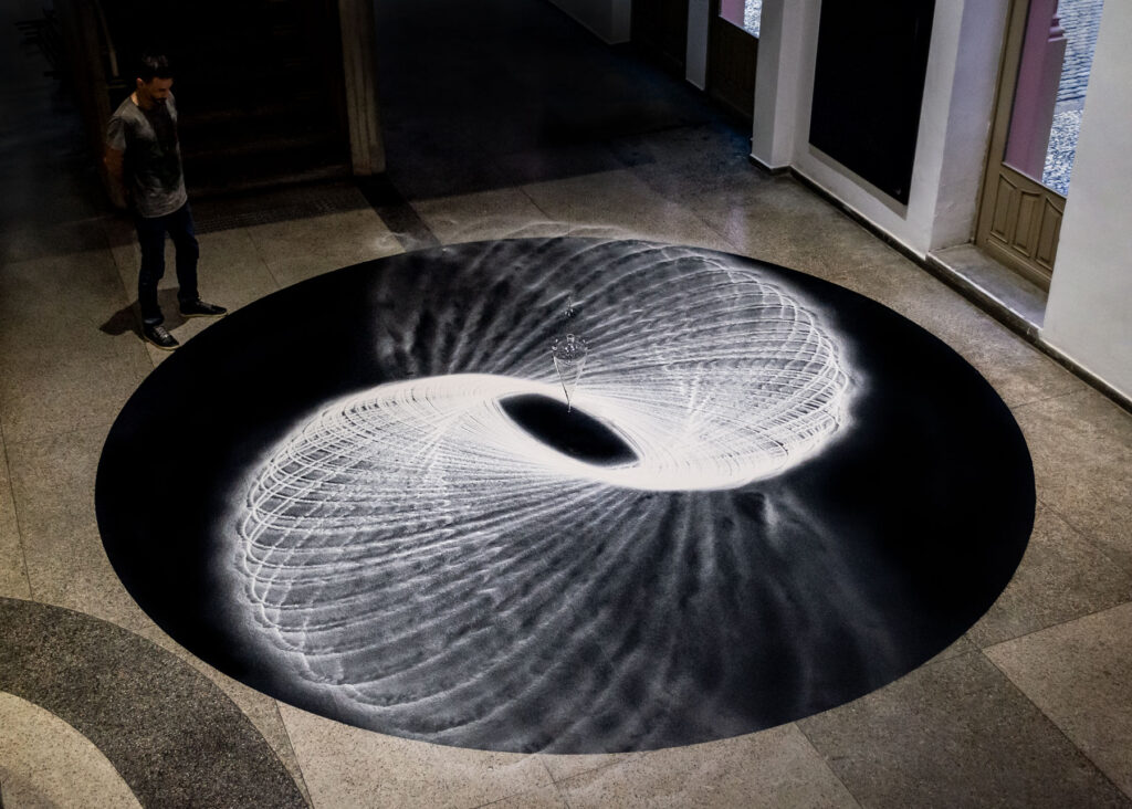 Movimento Pendular (2014), pêndulo de vidro liberando areia e desenhando no chão, obra de Felippe Moraes na 13ª Bienal do Mercosul