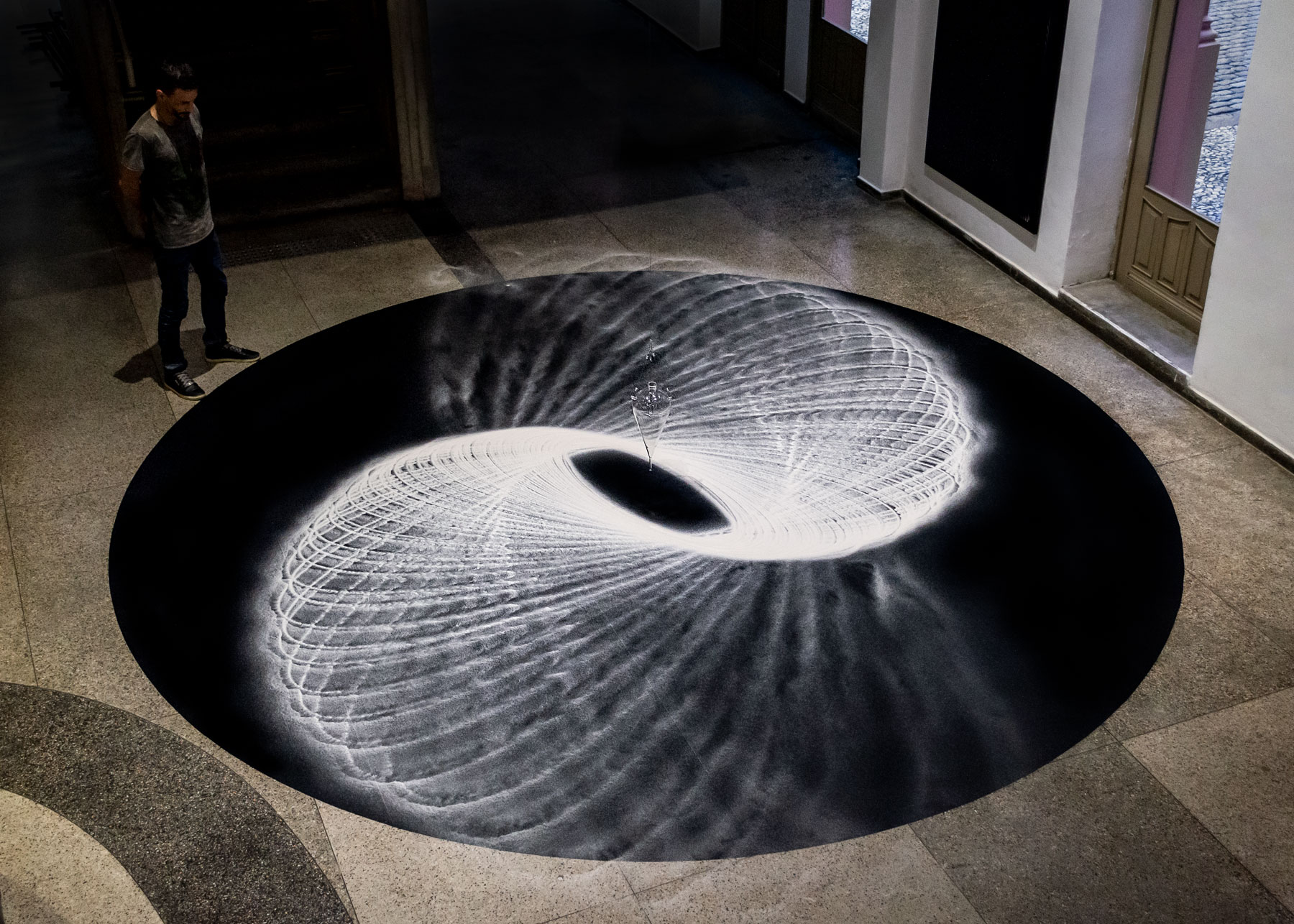 Instalação Movimento Pendular de Felippe Moraes com pêndulo desenhando curvas na areia.