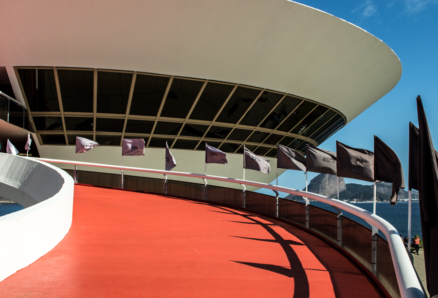 Instalação Progressão de Felippe Moraes com 26 bandeiras em progressão tonal na rampa do MAC Niterói