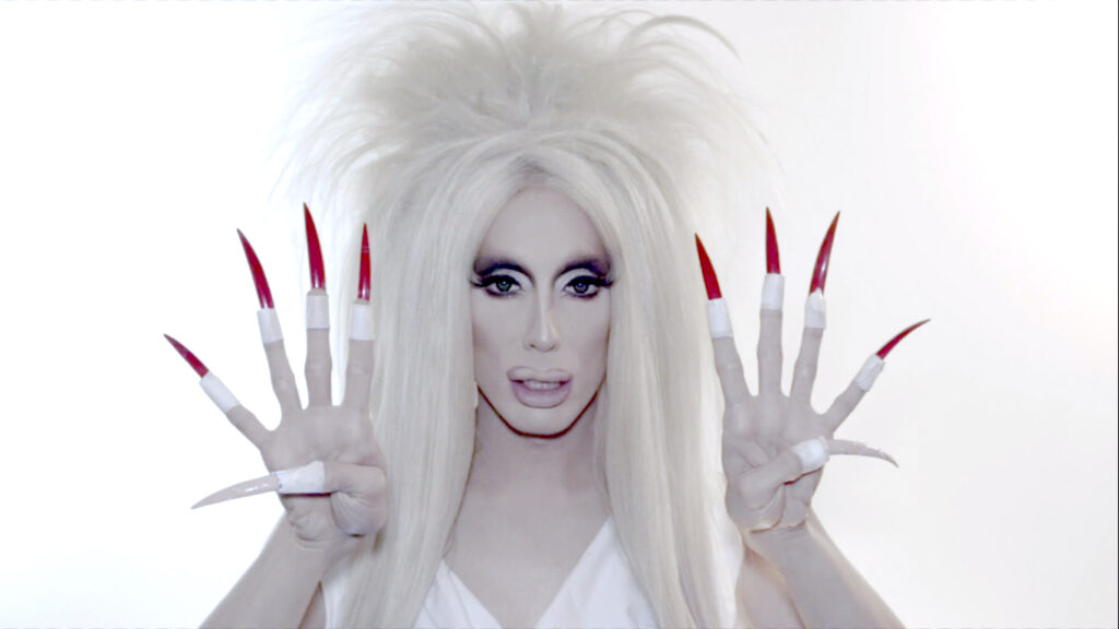 (2017) apresenta a performer Alaska Thunderfuck recitando os primeiros dígitos do número irracional conhecido como phi (1,618...). Historicamente associado a ideias de harmonia e perfeição formal na tradição estética ocidental, esse valor matemático surge no vídeo como matéria vocal e performática. Ao enunciar uma sequência potencialmente infinita, o trabalho transforma um conceito abstrato em gesto corporal e sonoro.

A figura queer diante desse símbolo clássico da história da arte tensiona noções tradicionais de beleza que moldaram o imaginário cultural do Ocidente. Ao deslocar essa referência matemática para o território da performance e da identidade, a obra questiona valores estéticos profundamente normativos que ajudaram a estabelecer concepções limitadoras do belo, muitas vezes vinculadas a perspectivas brancas e heteronormativas.

Realizado em uma única tomada, o vídeo enfatiza o olhar e a atuação da artista enquanto a sequência numérica avança de forma hipnótica. A repetição progressiva dos dígitos cria uma atmosfera que oscila entre rigor matemático e experiência quase meditativa. Ao tentar pronunciar uma sequência interminável, o trabalho evidencia os limites da linguagem e da razão diante da ideia de infinito.