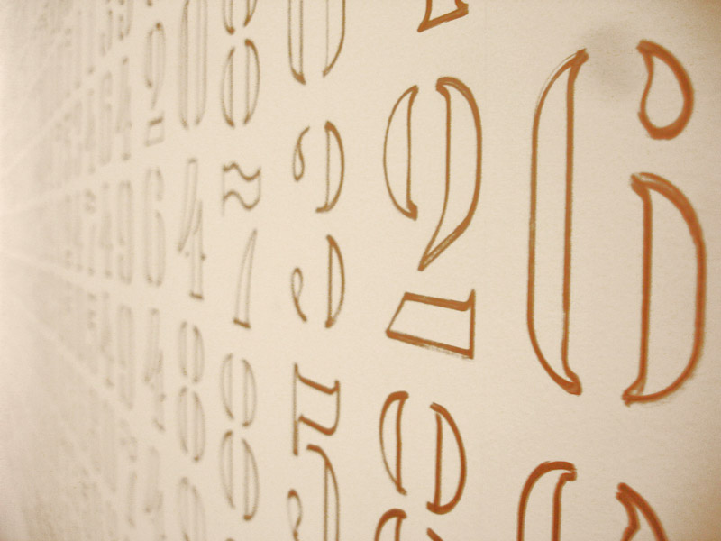 Números da constante pi escritos manualmente em dourado na parede na obra Pi de Felippe Moraes.