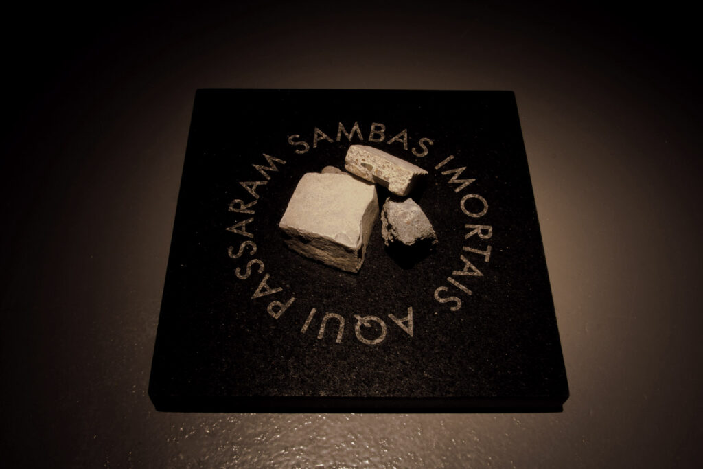 Detalhe da obra Aqui Passaram de Felippe Moraes mostrando inscrições com trechos da música Vai Passar de Chico Buarque gravados em pedra.