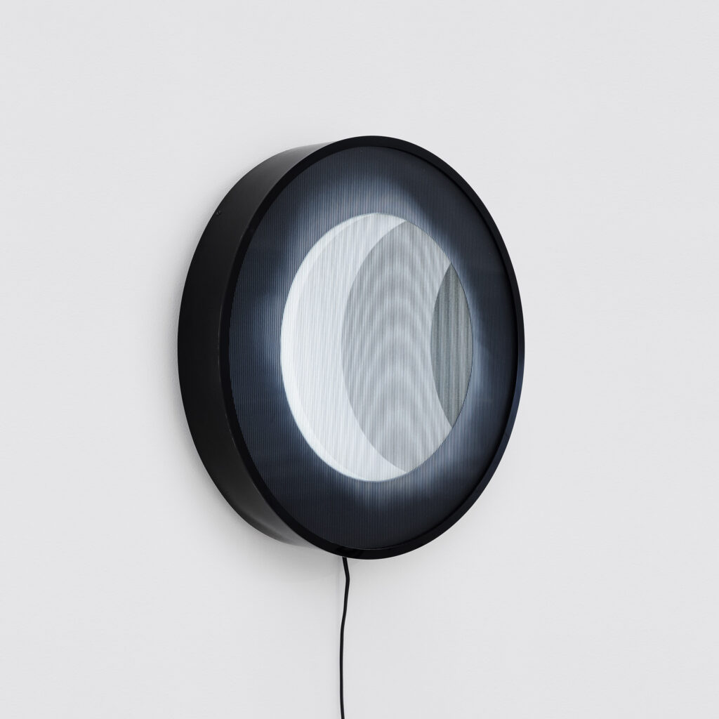 Obra Eclipse (2025) de Felippe Moraes com impressão lenticular circular retroiluminada representando eclipse solar.